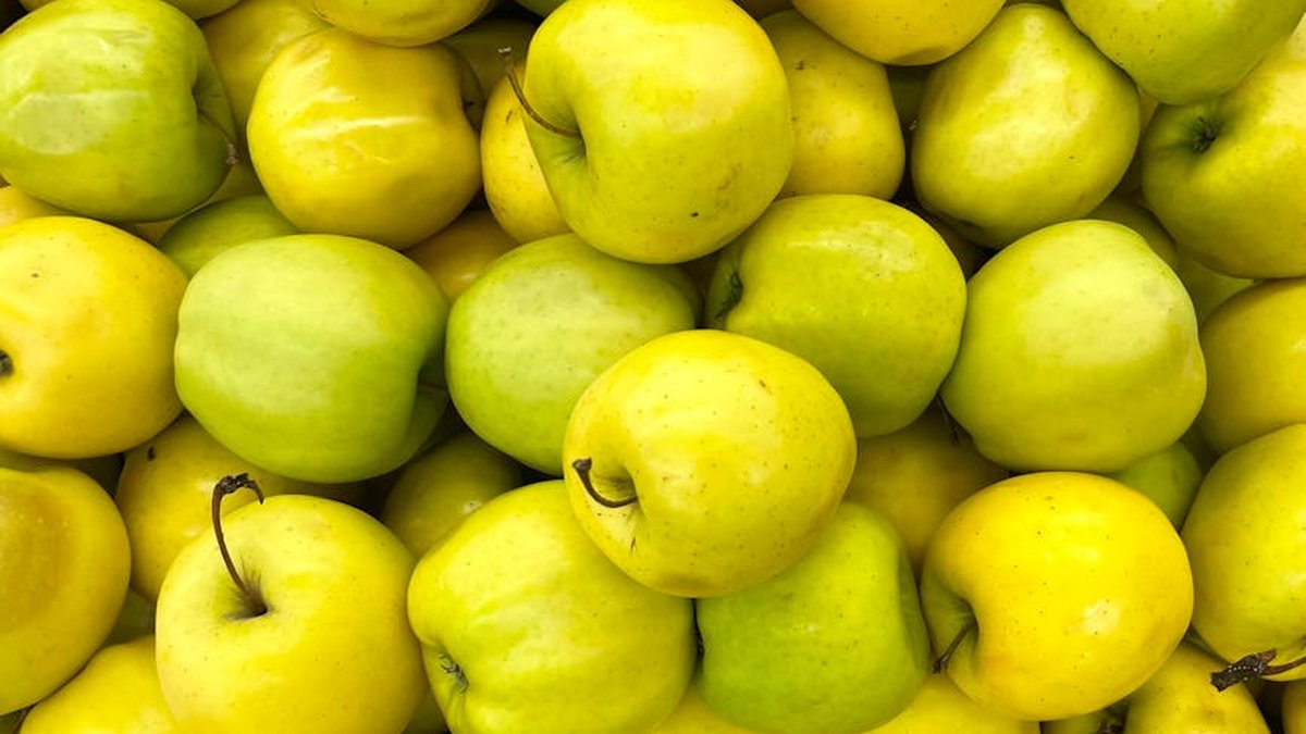 Close-up view of fresh yellow and green apples piled together, showcasing their natural abundance.