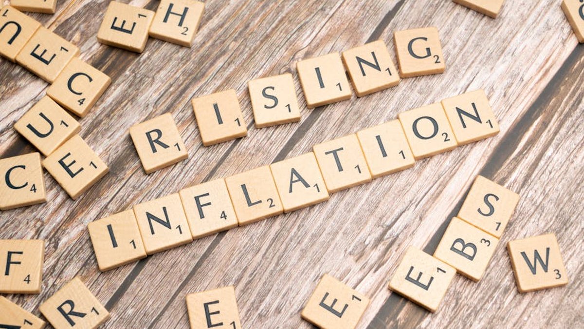Wooden letter tiles spell 'rising inflation' symbolizing economic concerns.